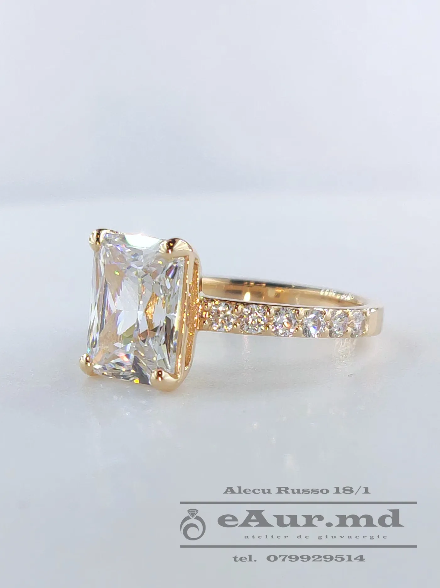 bijuterii din aur de calitate - model de inel de logodna din aur cu piatra dreptunghiulare mare si pietre rotunde mici lateral, trainic pentru a fi purtat pe termen indelungat